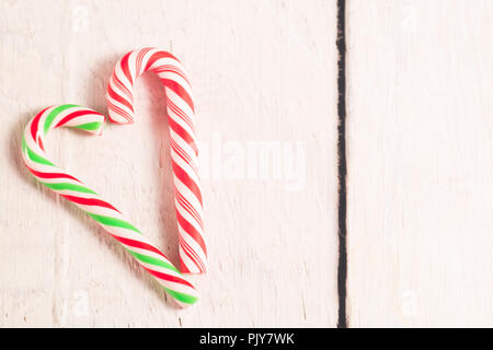 A forma di cuore ad candy canes su bianco rustico in legno scrivania. Foto Stock