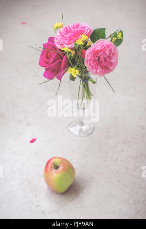 Arte vita ancora oggetto di un bouquet di rose rosa in un vaso e un apple Foto Stock