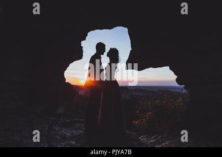 Wedding photo shoot a montagna Mangup in Crimea. Silhouette di amare giovane sposi alla luce del tramonto Foto Stock