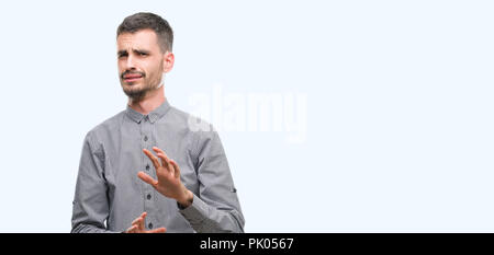 Giovane uomo parigamba disgustato espressione, orinato e timorosi facendo il disgusto di fronte perché la reazione di avversione. Con le mani alzate. Concetto di fastidiosi. Foto Stock