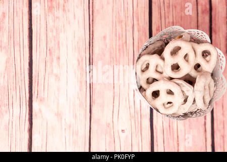 Vista dall'alto di una benna riempita con il rosa lampone yogurt immerso coperto pretzel. Utile per il giorno di San Valentino, copia extra spazio per il testo Foto Stock