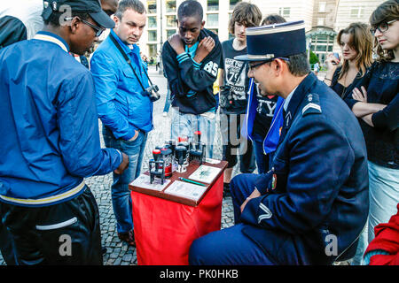 Uomo vestito da una gendarmeria francese si siede vicino alla Porta di Brandeburgo che offrono souvenir guerra fredda passa per le persone che visitano Berlino, Germania Foto Stock