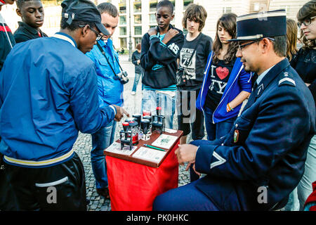 Uomo vestito da una gendarmeria francese si siede vicino alla Porta di Brandeburgo che offrono souvenir guerra fredda passa per le persone che visitano Berlino, Germania Foto Stock