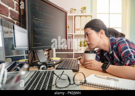 Bellissima femmina programmatore sensazione di esaurimento e tenendo il caffè cercando di rimanere sveglio. Foto Stock