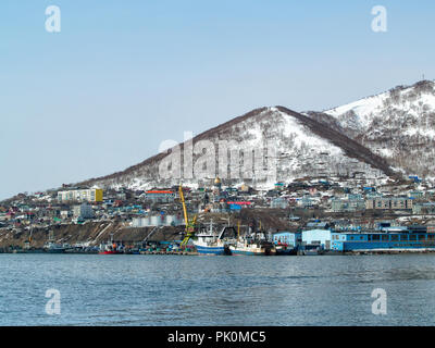 Le navi da pesca stand vicino la spiaggia nella baia Avacha ai piedi della coperta di neve di colline in inverno in Petropavlovsk-Kamchatsky, Russia Foto Stock