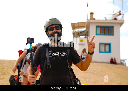 Parapendio mantenendo una azione di fotocamera e mostra segno di vittoria sul Monte Babadag e lui è pronto a lanciare o jumping Foto Stock