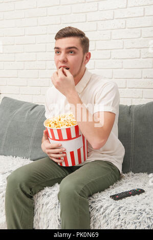 Un ragazzo adolescente mangiare popcorn Foto Stock