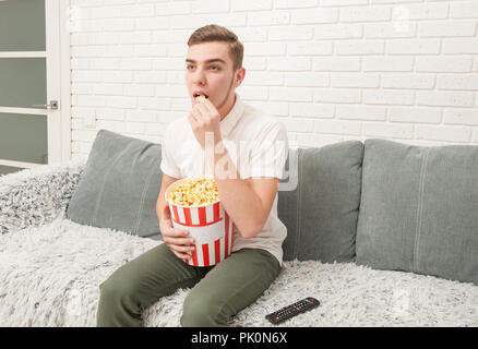 Un ragazzo adolescente mangiare popcorn Foto Stock