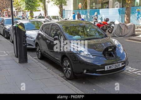 Una Nissan Leaf auto collegato a un elettrico rabboccare il punto su un Street a Londra, Inghilterra. Foto Stock