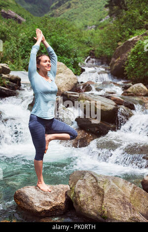 La donna a Yoga asana Vrikshasana posizione dell'albero a cascata all'aperto Foto Stock