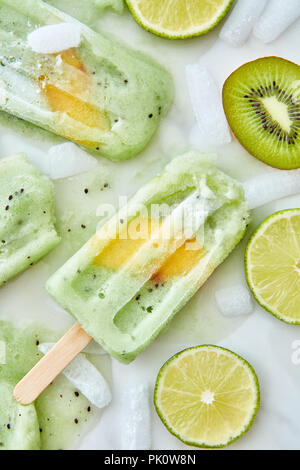 Per lecca-lecca di ghiaccio. Fusione dolci gelato con pezzi di frutta diversa, ghiaccio e schizzi su sfondo grigio. Un rinfrescante dessert estivo. Lay piatto Foto Stock