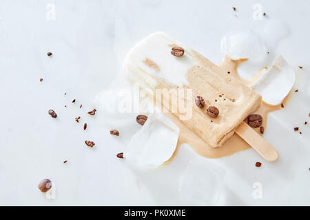 Il tiramisù popsicles gelato con i chicchi di caffè su un bastone di legno su sfondo marmo, vista dall'alto Foto Stock