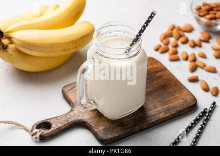 Banana frullato di proteina nel bicchiere in legno che serve board. Primo piano Foto Stock