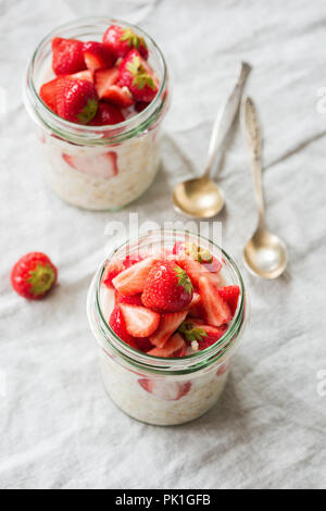 Per una notte di avena o farina di avena in vaso e rabboccato con le fragole. Mangiare sano, uno stile di vita sano, dieta e moderno stile di vita trendy concept Foto Stock