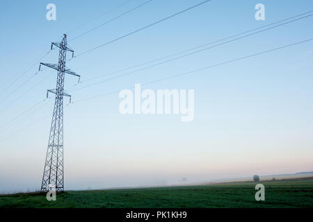 Supporta le linee elettriche ad alta tensione contro il cielo blu su sunrise. Industria elettrica. Foto Stock