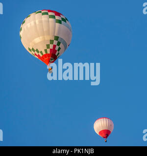 Paio di mongolfiere illuminate dalla luce del tramonto contro un bel cielo azzurro Foto Stock