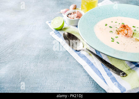 Mediterraneo italiano cibo tradizionale, fatti in casa a base di pesce vegetale zuppa cremosa con gamberetto boreale, calce e erbe aromatiche, azzurro sfondo concreto copia Foto Stock