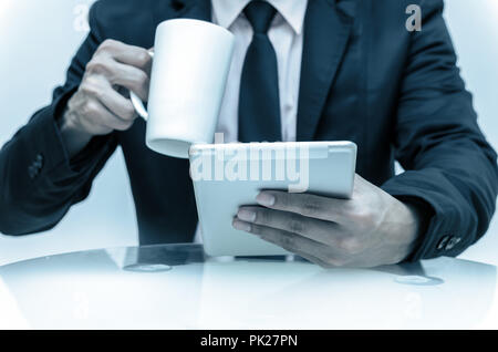 Closeup imprenditore tenendo compressa, tazza di caffè e di lavoro sul luogo di lavoro, la concezione di business Foto Stock