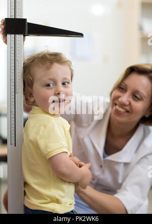 Medico donna Misurazione altezza del ragazzino in clinica Foto Stock