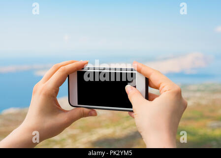 Mani femminili di scattare una foto del paesaggio. Ritagliato shot vista della donna di mani smart phone con la copia in bianco sullo schermo di spazio per le foto. Foto Stock