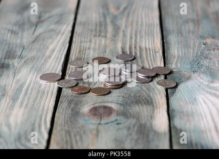 Diverse monete metalliche giacciono su di un tavolo di legno Foto Stock