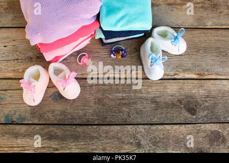 Baby scarpe, abbigliamento e ciucci rosa e blu sul vecchio sfondo di legno. Vista dall'alto. Lay piatto. Foto Stock