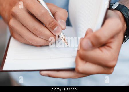 L'uomo scrivere note in un notebook. Mano che tiene la penna Foto Stock