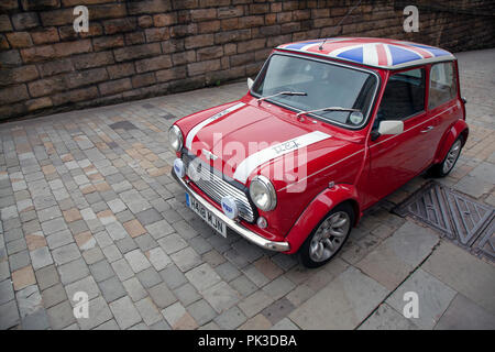 Un Rosso Mini Cooper wth un raccordo martinetto tetto da John Cooper versione del mini parcheggiata su una strada acciottolata a Huddersfield Foto Stock