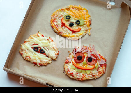 La pizza di Halloween con mostri, al di sopra della scena con decor e su una carta craft casella Sfondo, idea per la casa parte cibo, facile, sano e delizioso cibo divertente Foto Stock