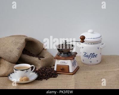 Ancora con la vita di un vecchio macinino da caffè, una tazza di caffè e il vecchio caffè in porcellana stagno Foto Stock