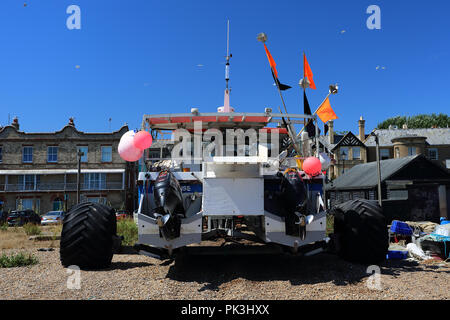 Una barca spiaggiata su un rimorchio sulla spiaggia di ciottoli a Aldeburgh, Suffolk, Regno Unito Foto Stock
