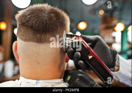 Bel uomo barbuto al barbiere, barbiere al lavoro. Chiudere fino alla nuca. Foto Stock