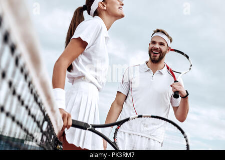 Essi giocare come una squadra. Bella giovane donna e uomo azienda racchetta da tennis e discutendo insieme Foto Stock