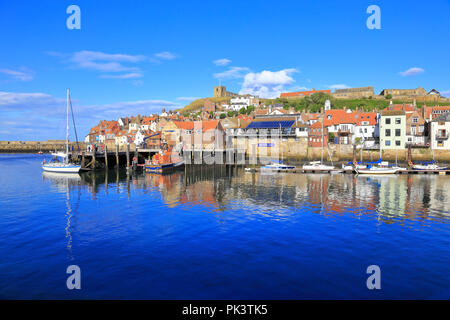 RNLI scialuppa di salvataggio e barche nel porto di inferiore sotto la chiesa di Saint Mary, Whitby, North Yorkshire, Inghilterra, Regno Unito. Foto Stock