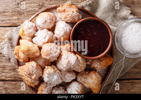 Deliziose ciambelle fritte sono serviti con confettura di lamponi e zucchero a velo close-up su una piastra sul tavolo. parte superiore orizzontale vista da sopra Foto Stock