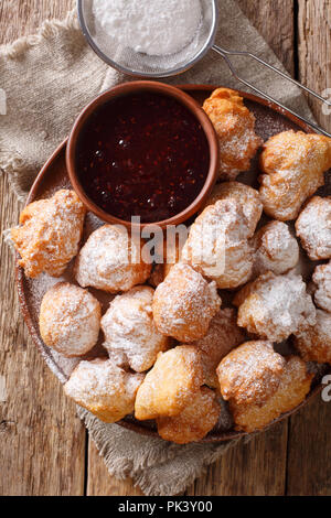 Deliziose ciambelle fritte sono serviti con confettura di lamponi e zucchero a velo close-up su una piastra sul tavolo. Verticale in alto vista da sopra Foto Stock