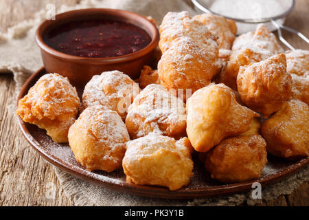 Cibo albanese: ciambelle fritte sono serviti con confettura di lamponi e zucchero a velo close-up su una piastra sul tavolo orizzontale. Foto Stock