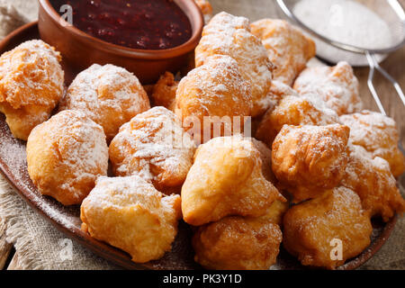 Deliziose ciambelle fritte sono serviti con confettura di lamponi e zucchero a velo close-up su una piastra sul tavolo orizzontale. Foto Stock