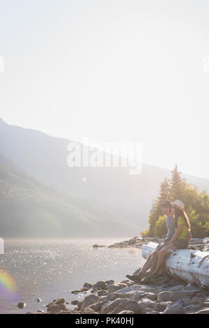 Giovane rilassante sul registro di legno vicino a Riverside Foto Stock