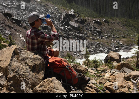 Escursionista maschio guardando attraverso il binocolo in campagna Foto Stock