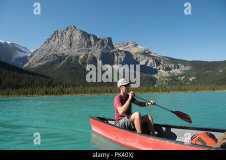 L'uomo remare una barca sul fiume Foto Stock