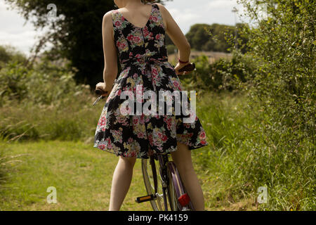 Donna bicicletta equitazione nel campo Foto Stock