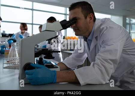 Scienziato maschio mediante microscopio Foto Stock