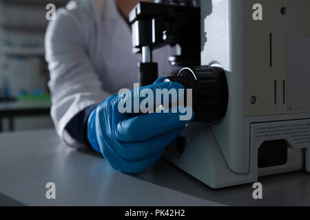 Scienziato maschio mediante microscopio Foto Stock