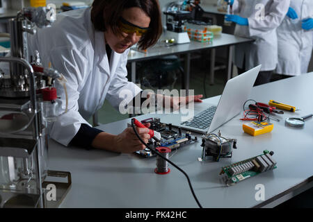 Donna scienziato saldatura scheda di circuito Foto Stock