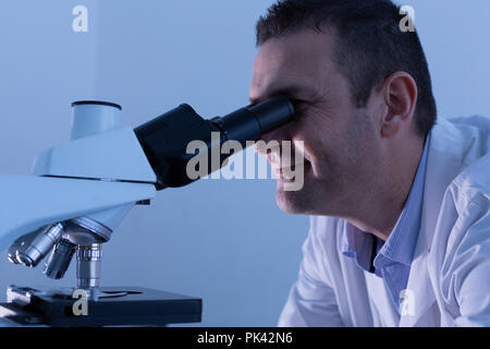 Scienziato maschio mediante microscopio Foto Stock