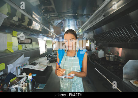 Donna cameriera ordini di scrittura sul blocco note Foto Stock