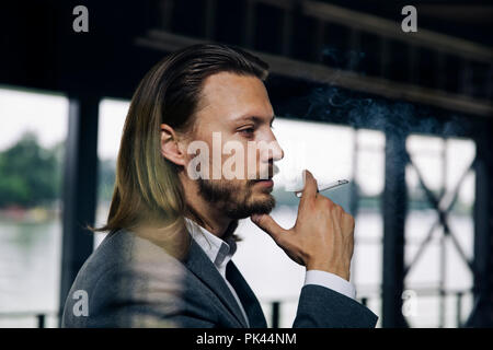 Vista laterale al giovane imprenditore godendo il suo sigaro in pausa Foto Stock