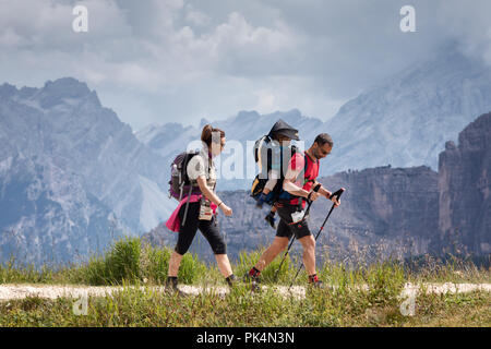 Cortina d'Ampezzo, Italia - 18 agosto 2018: una famiglia di escursionisti passeggiate sul sentiero di montagna, il padre porta il suo figlio sulle sue spalle. In backgro Foto Stock