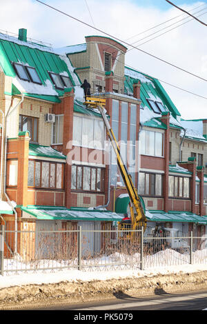Il servizio di pulizia pulisce la neve dal tetto della casa. Foto Stock